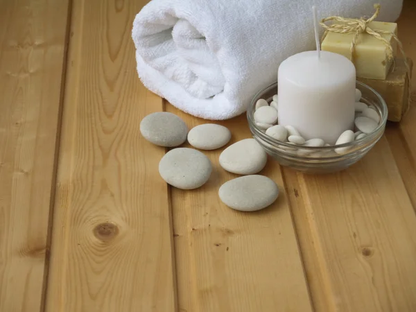 Ręcznik, mydło, Świeca i kamienie na podłoże drewniane — Zdjęcie stockowe