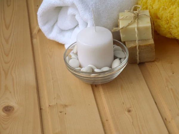Полотенце, мыло, свеча и губка на деревянном фоне — стоковое фото