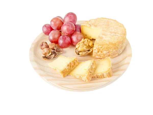 Fromage, noisettes, noix et raisin rouge sur la planche de bois — Photo