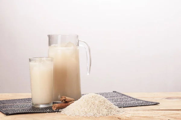 Sürahi ve bardak Horchata, pirinç ve tarçınlı ahşap masa..