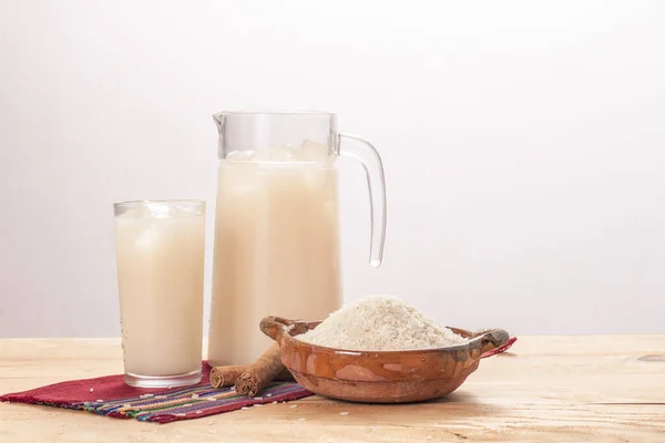 Sürahi ve bir bardak Horchata, kilden bir tabakta pirinç ve tarçın..