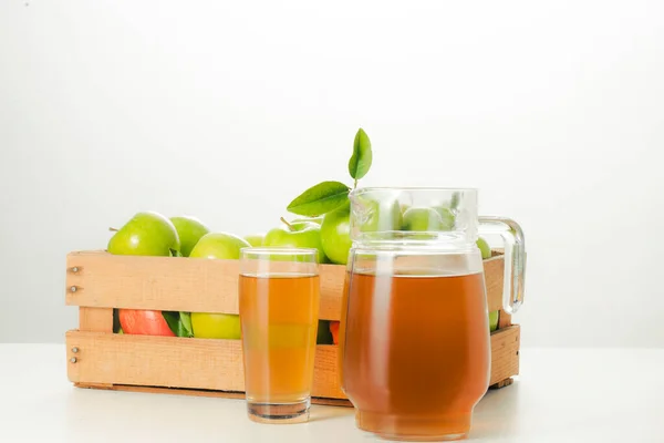 Bardakta elma suyu, beyaz arka planda bir kutu taze kesilmiş yeşil elma..