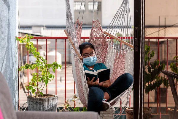 Maskeli bir kız kitap okuyor, Coronavirus ya da covid-19 bitene kadar evde kalıyor..