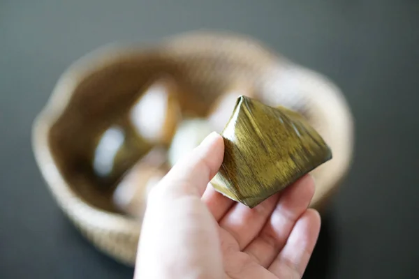 Ruka drží plněné těsto pyramida dezert na koš vzor bambus — Stock fotografie