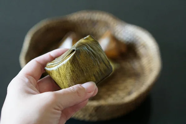 Hand holds Stuffed Dough Pyramid Dessert On bamboo pattern basket — Stock Photo, Image