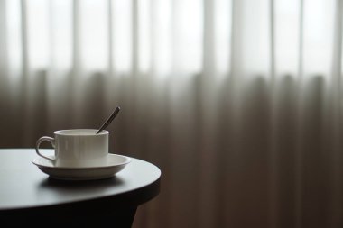 otel odasında bir kanepe koltuk tarafından masada beyaz kahve fincanı