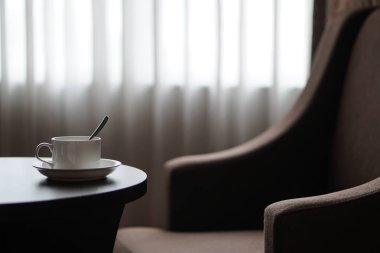 otel odasında bir kanepe koltuk tarafından masada beyaz kahve fincanı