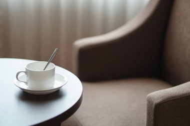 otel odasında bir kanepe koltuk tarafından masada beyaz kahve fincanı
