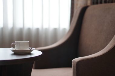 otel odasında bir kanepe koltuk tarafından masada beyaz kahve fincanı