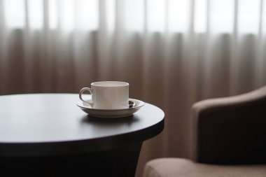 otel odasında bir kanepe koltuk tarafından masada beyaz kahve fincanı