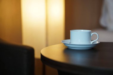 otel odasında bir kanepe koltuk tarafından masada beyaz kahve fincanı