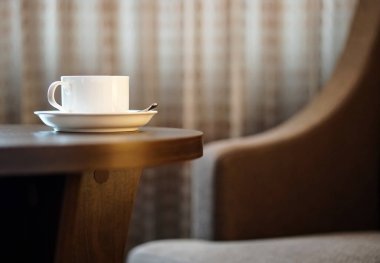 otel odasında bir kanepe koltuk tarafından masada beyaz kahve fincanı