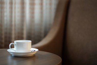otel odasında bir kanepe koltuk tarafından masada beyaz kahve fincanı