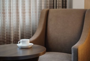 otel odasında bir kanepe koltuk tarafından masada beyaz kahve fincanı