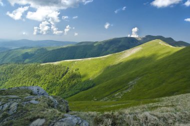 Bulutlu yaz göğün altında inanılmaz yeşil dağ zinciri taşlarla
