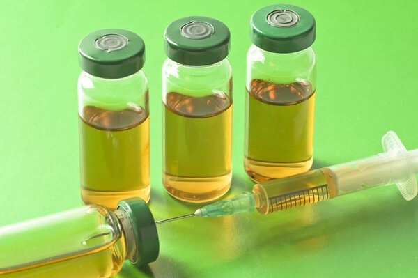 Стерильные медицинские ампулы с лекарственным раствором, ампулы и шприц изолированы на светло-зеленом фоне
