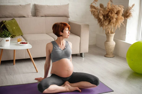 Evdeki egzersiz topunun yanında oturan güzel hamile bir kadının portresi..
