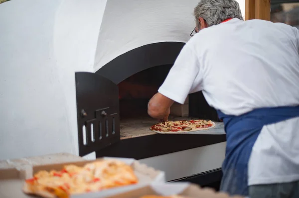 Baker puts the fresh pizza in the oven ストック画像