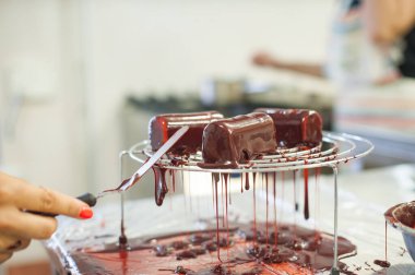 Şekerci çikolatalı krema ile tatlı koyar. Mutfakta tatlı yapma süreci.