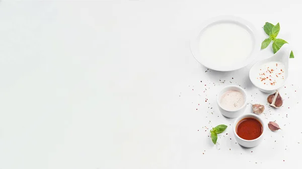 Beyaz arka planda farklı sos ve baharatlar var..