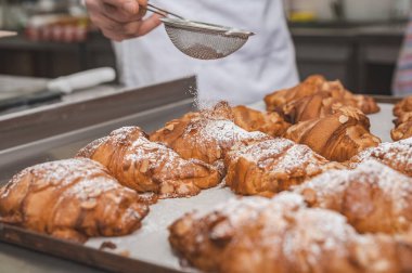 Badem gevreği ve kremalı kruvasan. Pişirme tepsisinde kruvasan. Önplana odaklan.