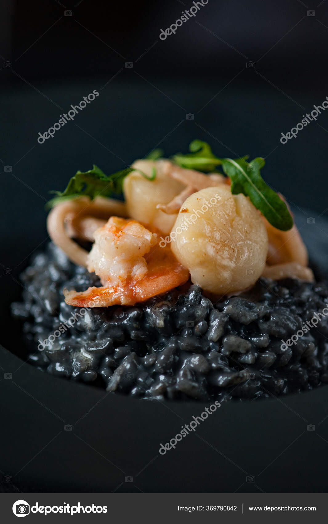 Black risotto with shrimp, scallops and cuttlefish ink. Stock Photo by