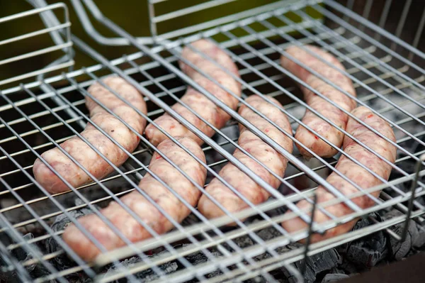 Raw sausages on the grill.. Fresh sausage grilling outdoors on a barbecue grill.