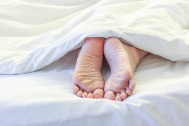 Beyaz yatak odasında uyuyan kadın ayakları 