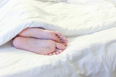 Beyaz yatak odasında uyuyan kadın ayakları 
