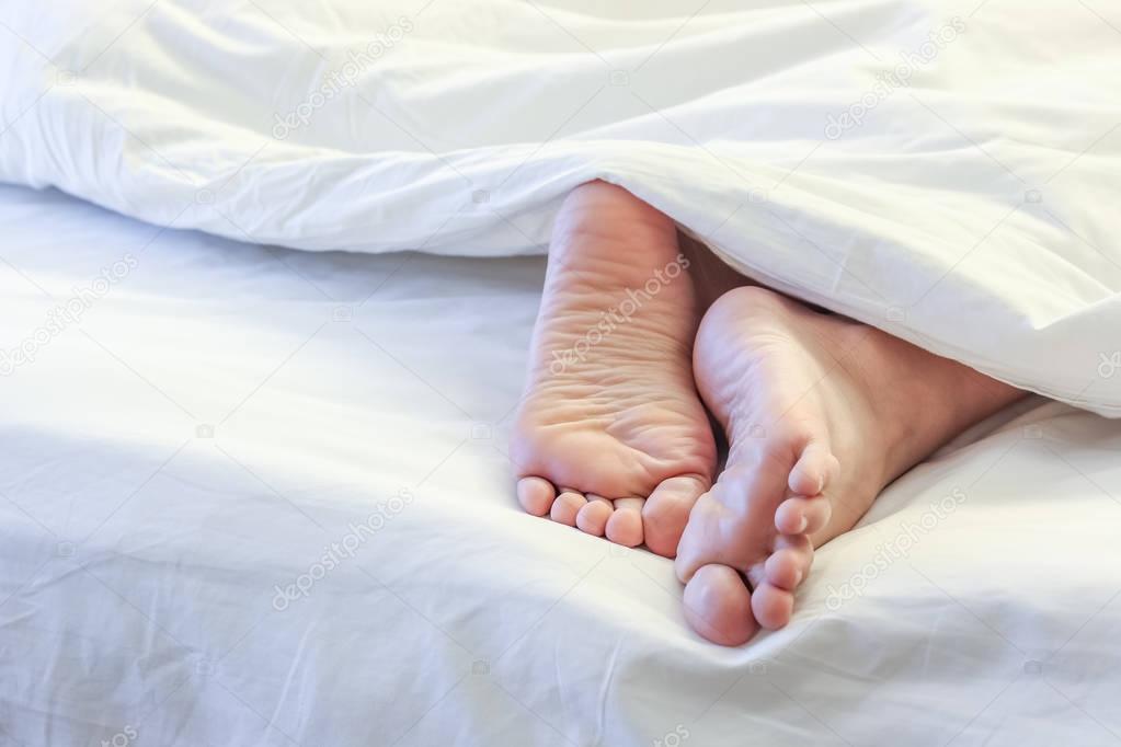 Feet of sleeping woman in white bed room 