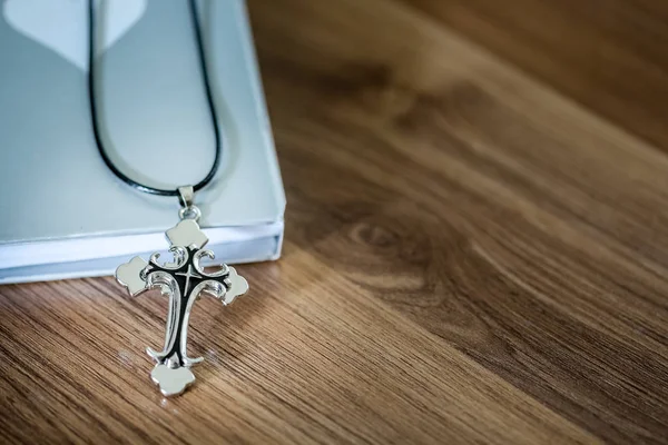 Cross pendant over the book on the wooden table with copy space — Stock Photo, Image