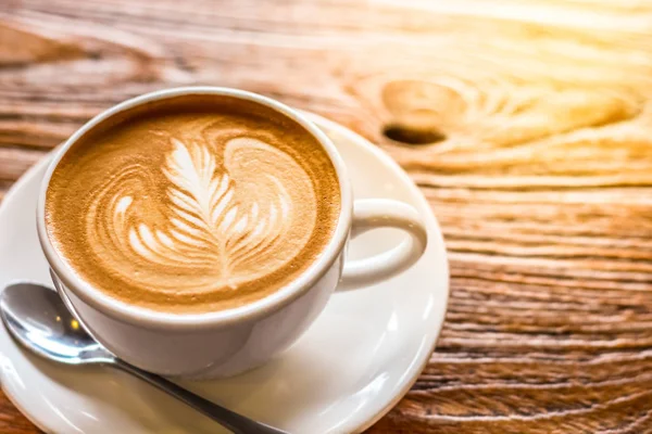 Taza de café arte latte con cuchara y plato en la corteza marrón hermoso fondo textura con luz cálida —  Fotos de Stock