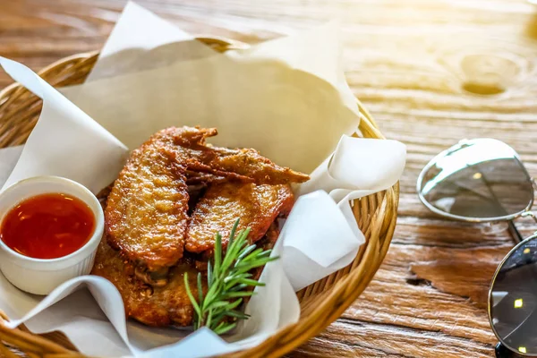 Kızarmış tavuk kanadı biber sosu kahverengi kabuğu arka plan üzerinde daldırma ile sepette güneş gözlüğü ile dekore edilmiştir. 