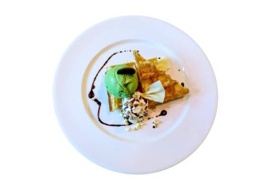 Beyaz tabakta krem şanti ile birlikte kek ve yeşil çay dondurma tatlı yaptı