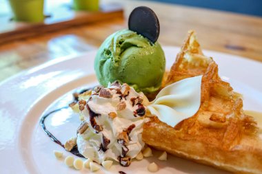 Beyaz tabakta krem şanti ile birlikte kek ve yeşil çay dondurma tatlı yaptı