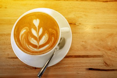 Bir fincan sütlü sanat kahvesi ve ılık ışık.