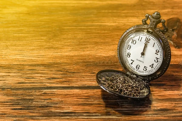 luxury vintage black pocket watch on wooden table, abstract for time concept with copy space, sepia effect