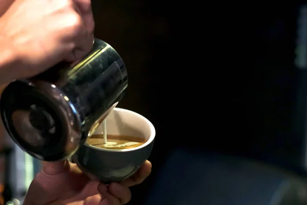 Närbild Barista händer hälla varm mjölk i kaffekopp för Makin Stockfoto