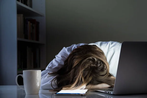 Müde Person schläft am Schreibtisch im Home Office mit eingeschaltetem Computer und Tablet-PC — Stockfoto