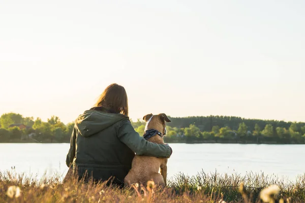 Flicka och sällskapsdjur hund nära sjön vid solnedgången — Stockfoto