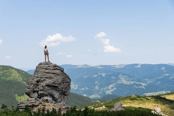 Genç kadın turist kırsal dağ alan kaya üstünde duruyor ve Ukraynalı Karpat Dağları güzel panoramik sahne görünüyor