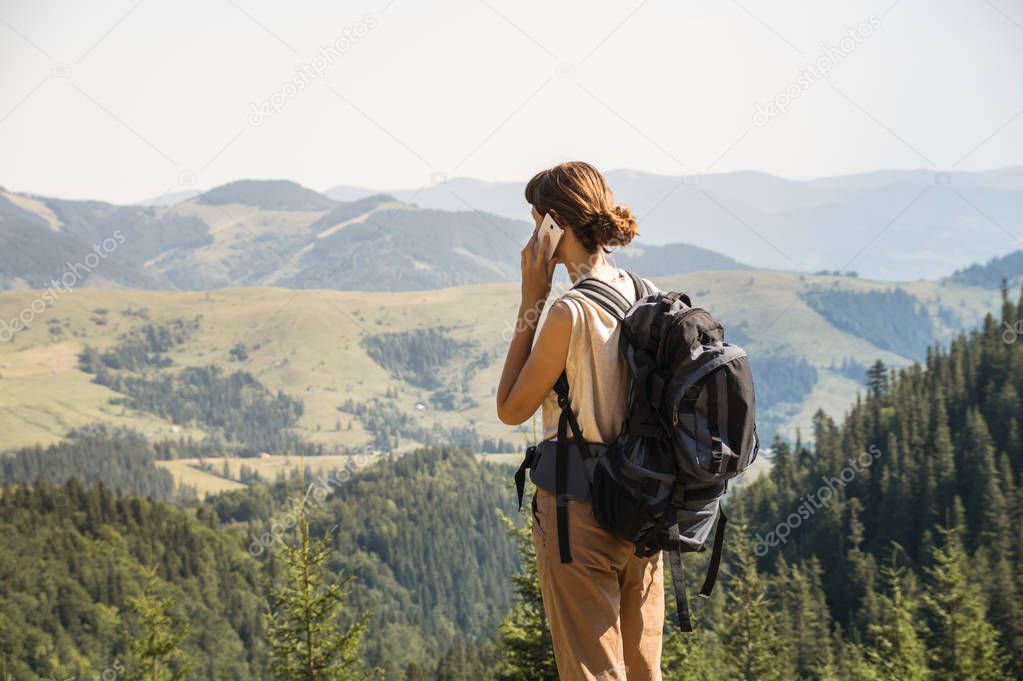 Young female backpacker uses mobile phone to communicate in rural mountain area of ukrainian carpathian mountains
