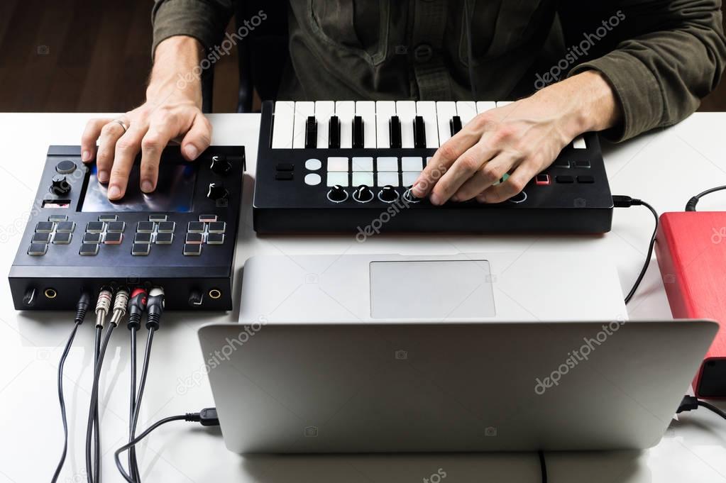 Male person controlling or mixing electronic music track on computer with help of modern effect processors and software controllers
