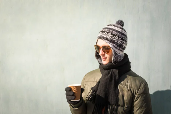 Joven en ropa de invierno sostiene taza de café —  Fotos de Stock
