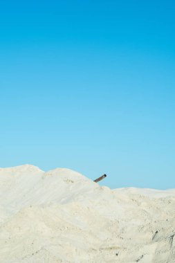 Beyaz kumları, mavi gökyüzü ve paslı boru
