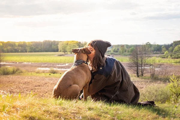 Menina bonita caminhadas sentar na colina e beijar cão de estimação no passeio — Fotografia de Stock