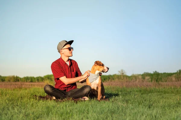 Yakışıklı genç erkek köpek sahibi ve staffordshire terrier köpek çim otur — Stok fotoğraf