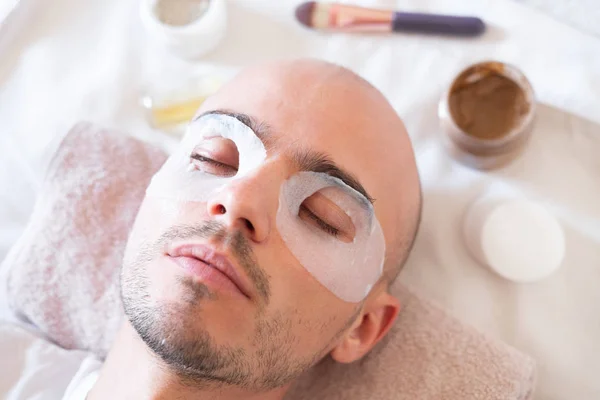 Man with moisturizing mask for skin around the eyes.