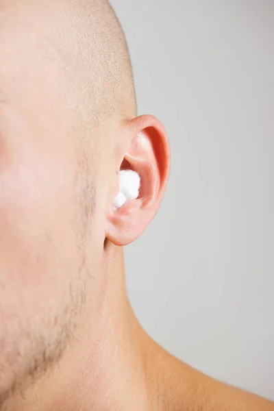 Close up view of a young man with sterile cotton wool in his ear
