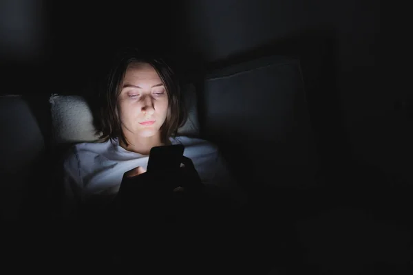 Femme au lit utilise le téléphone tard dans la nuit . — Photo
